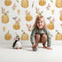 Lovely child standing in front of Whimsy Tots Pumpkin Patch Whimsy Wallpaper in White with pumpkin, bird, heart, leaf in design. Lovely child standing in front of Whimsy Tots Pumpkin Patch Whimsy Wallpaper in White with pumpkin, bird, heart, leaf in design.