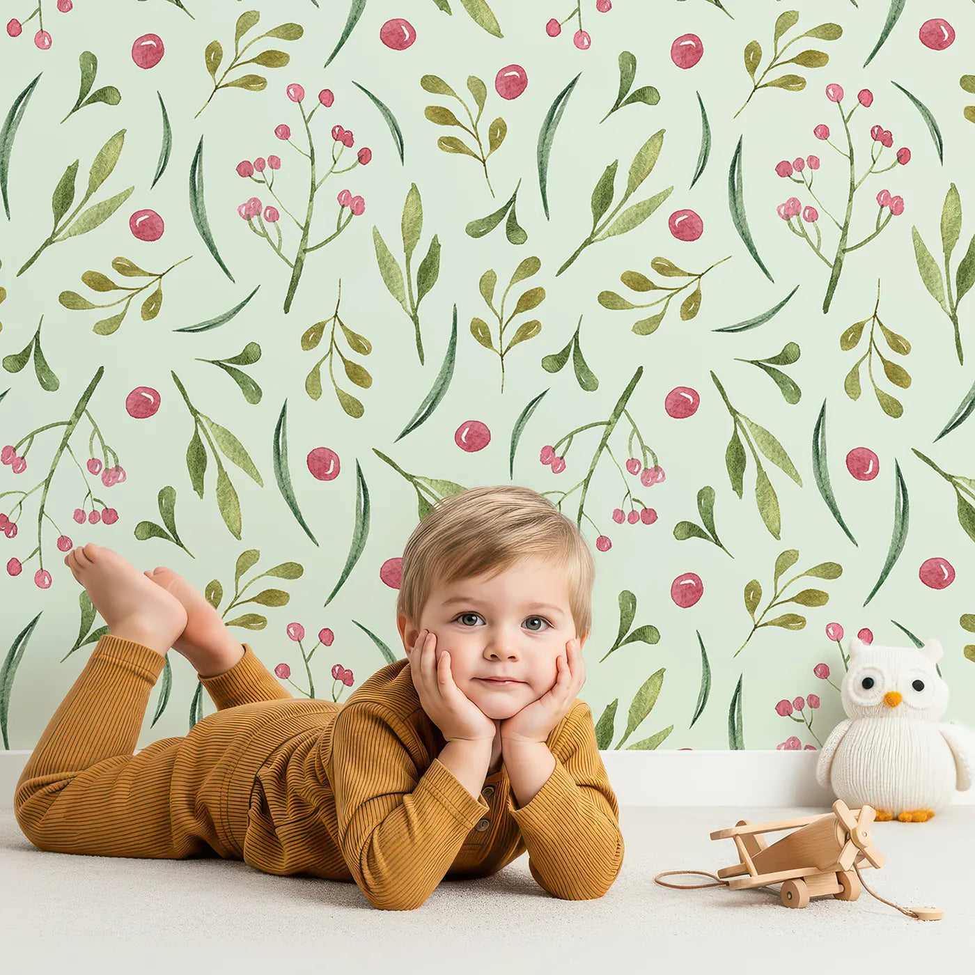 Lovely child standing in front of Whimsy Tots Berry Leaf Doodle Wallpaper in Mint Green with berry, leaf, branch, dot in design.