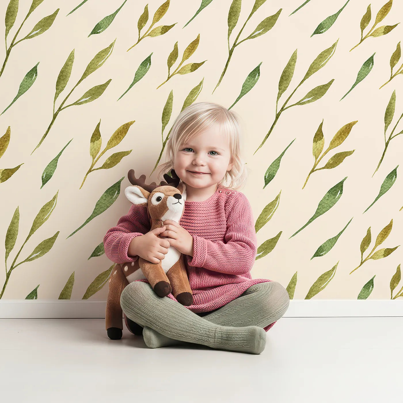 Lovely child standing in front of Whimsy Tots Wandering Willow Sprigs Wallpaper in Cream with leaf, sprig, branch in design.