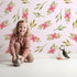 Lovely child standing in front of Whimsy Tots Whimsy Bloom Sprays Wallpaper in Blush Pink with flower, leaf, bloom, spray in design. Lovely child standing in front of Whimsy Tots Whimsy Bloom Sprays Wallpaper in Blush Pink with flower, leaf, bloom, spray in design.