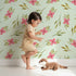 Lovely child standing in front of Whimsy Tots Whimsy Bloom Sprays Wallpaper in Mint Green with flower, leaf, bloom, spray in design. Lovely child standing in front of Whimsy Tots Whimsy Bloom Sprays Wallpaper in Mint Green with flower, leaf, bloom, spray in design.