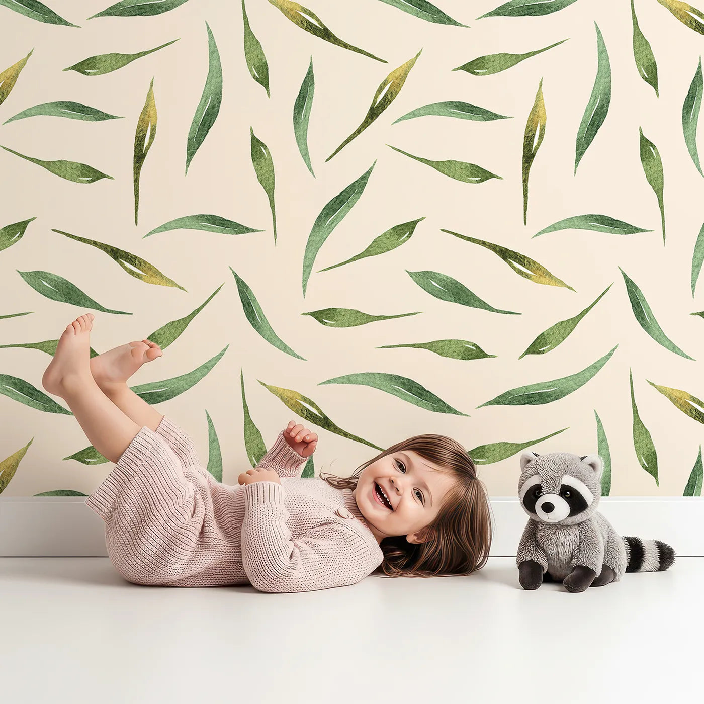 Lovely child standing in front of Whimsy Tots Whimsy Leaf Scatter Wallpaper in Cream with leaf, spray, greenery, foliage in design.