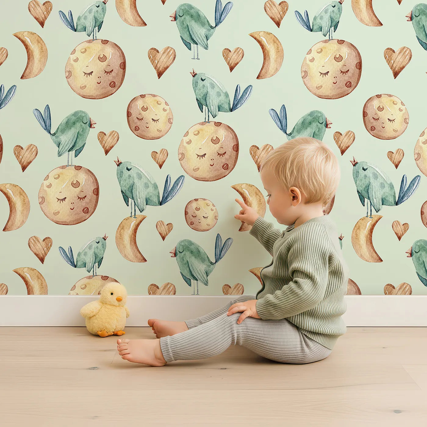 Lovely child standing in front of Whimsy Tots Moon Melody Wallpaper in Mint Green with bird, moon, heart, star in design.