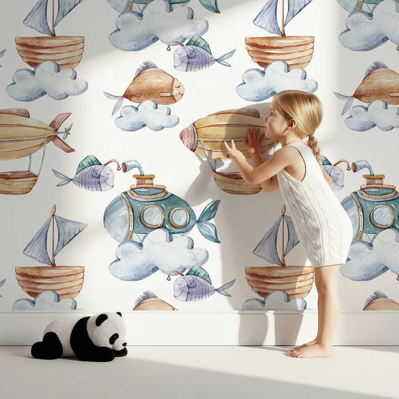 Lovely child standing in front of Whimsy Tots Sky Explorers Wallpaper in White with fish, submarine, balloon, ship, sky, cloud in design.