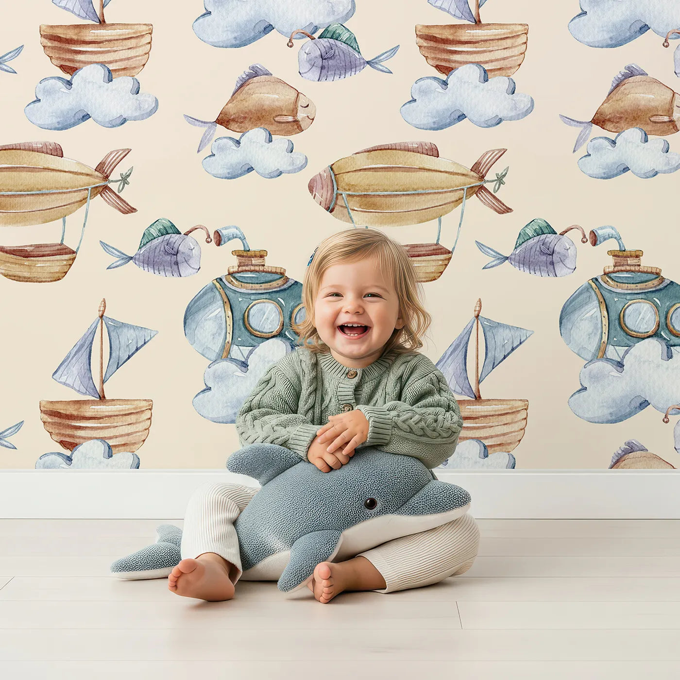 Lovely child standing in front of Whimsy Tots Sky Explorers Wallpaper in Cream with fish, submarine, balloon, ship, sky, cloud in design.