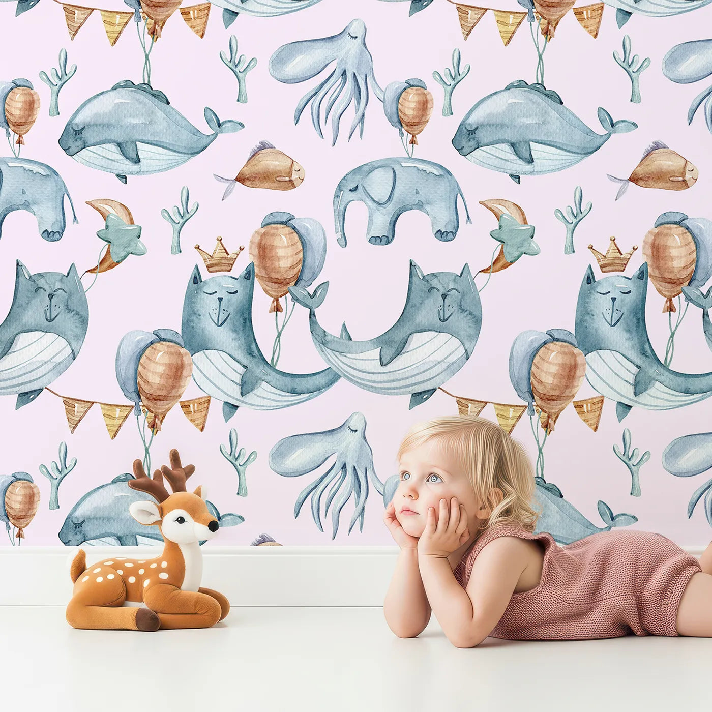 Lovely child standing in front of Whimsy Tots Whale Balloon Parade Wallpaper in Blush Pink with whale, balloon, octopus, bunting, seaweed, crown in design.
