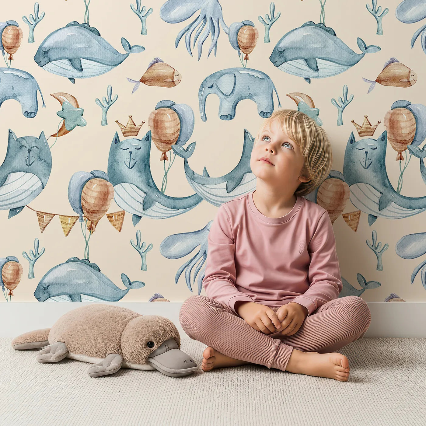 Lovely child standing in front of Whimsy Tots Whale Balloon Parade Wallpaper in Cream with whale, balloon, octopus, bunting, seaweed, crown in design.