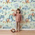 Lovely child standing in front of Whimsy Tots Whale Balloon Parade Wallpaper in Mint Green with whale, balloon, octopus, bunting, seaweed, crown in design. Lovely child standing in front of Whimsy Tots Whale Balloon Parade Wallpaper in Mint Green with whale, balloon, octopus, bunting, seaweed, crown in design.
