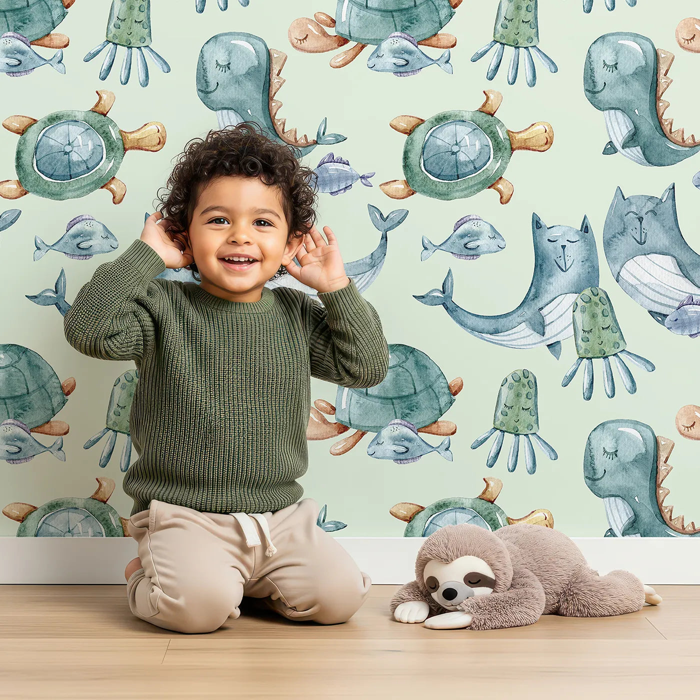 Lovely child standing in front of Whimsy Tots Ocean Daydream Creatures Wallpaper in Mint Green with whale, fish, turtle, octopus, dinosaur, seaweed in design.