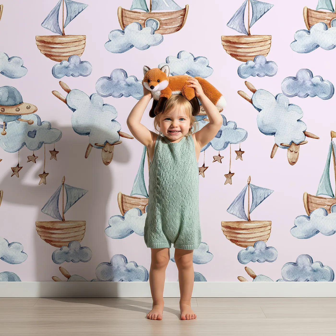Lovely child standing in front of Whimsy Tots Cloud Sailor Dreams Wallpaper in Blush Pink with ship, cloud, sheep, star, sail in design.