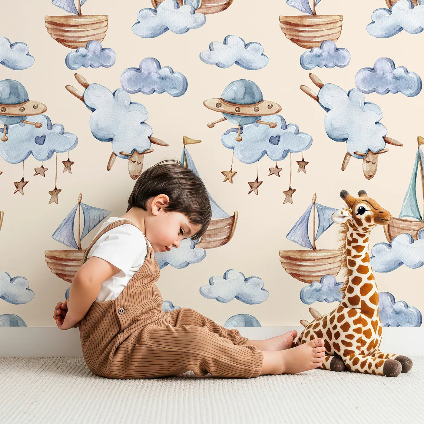 Lovely child standing in front of Whimsy Tots Cloud Sailor Dreams Wallpaper in Cream with ship, cloud, sheep, star, sail in design.
