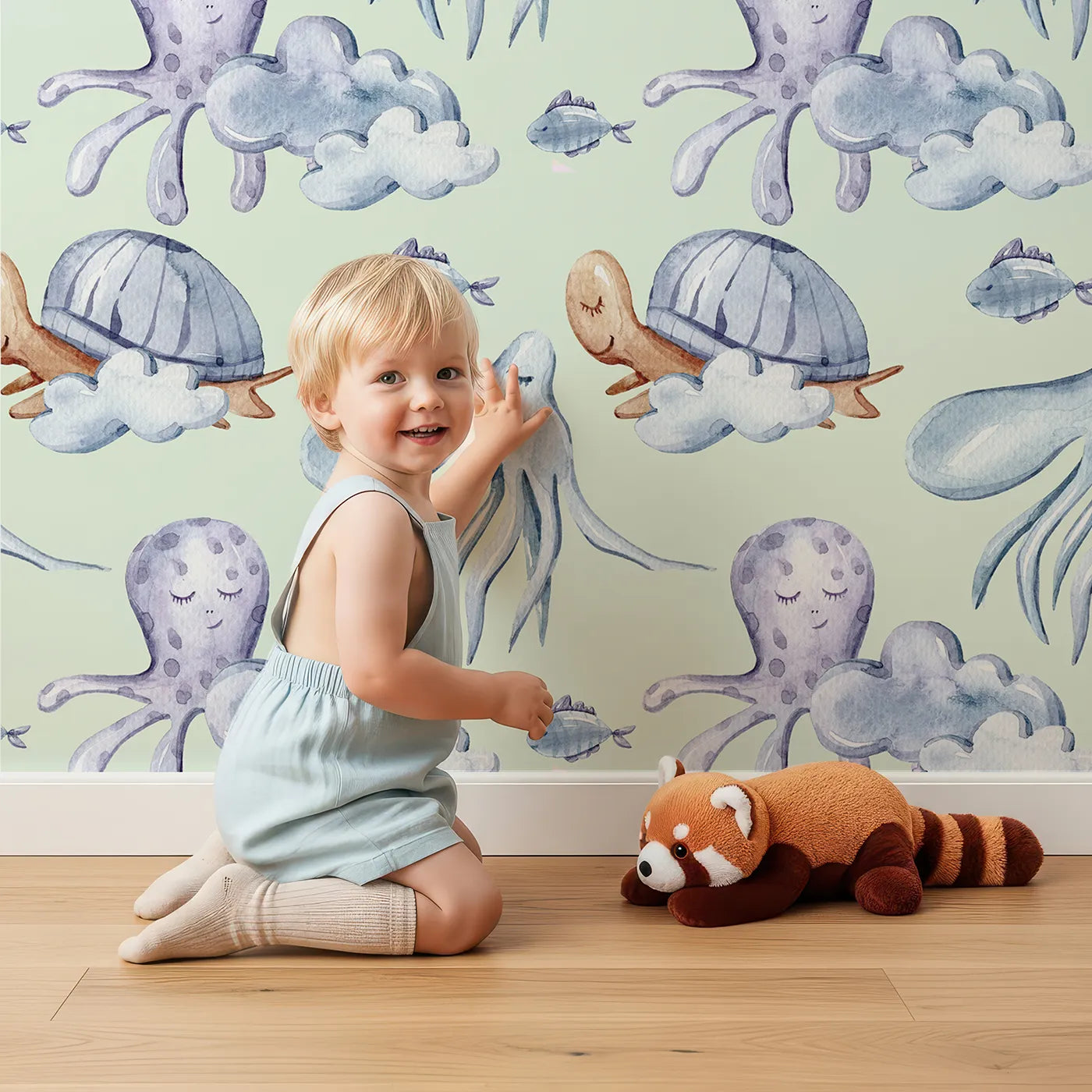 Lovely child standing in front of Whimsy Tots Ocean Dreams Wallpaper in Mint Green with cloud, turtle, octopus, squid, fish in design.