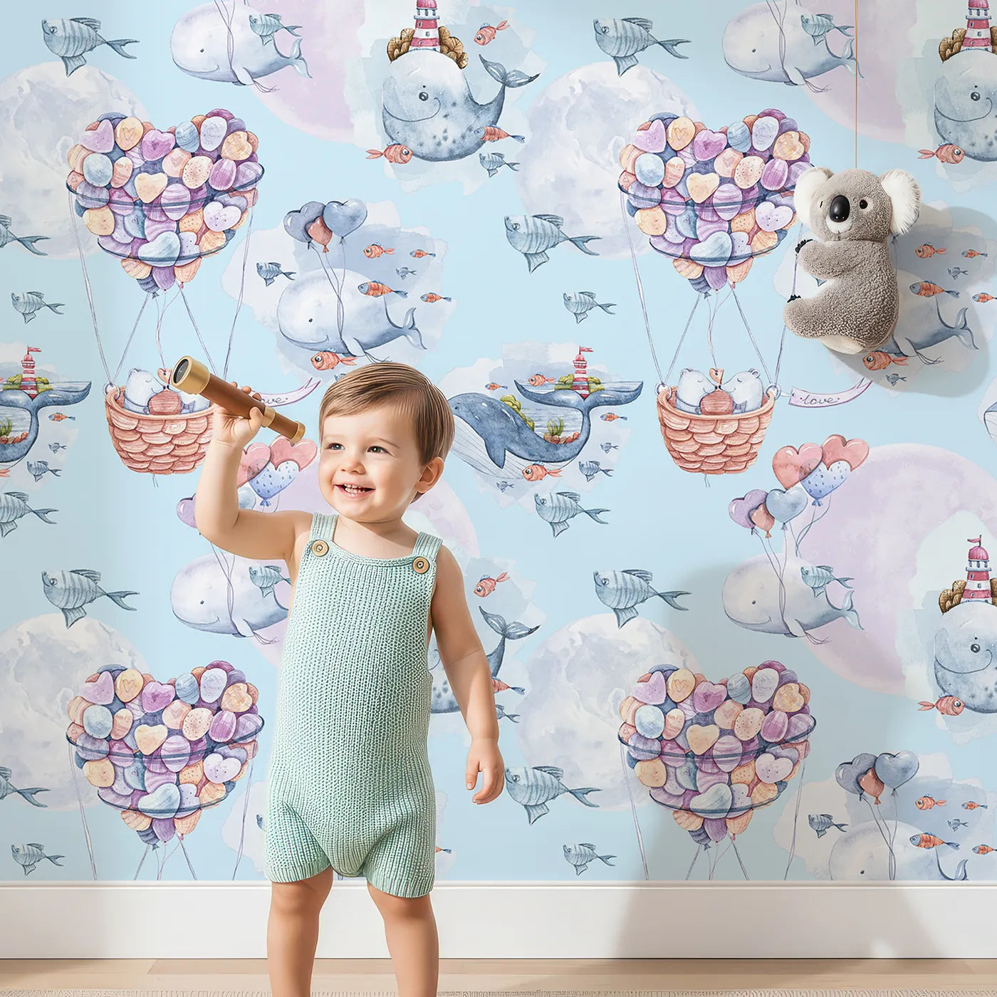 Lovely child standing in front of Whimsy Tots Whales of Love Wallpaper in Blue with whale, balloon, heart, lighthouse, bear, fish in design.