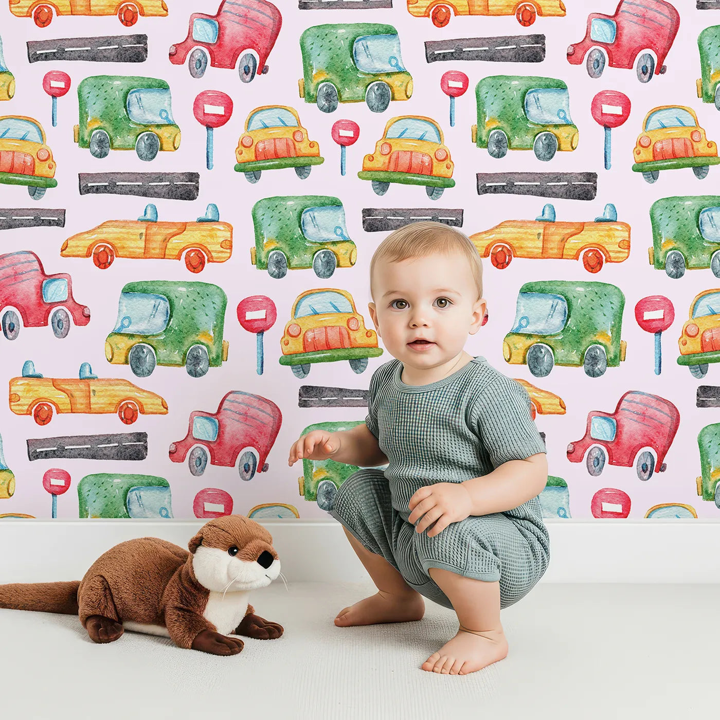 Lovely child standing in front of Whimsy Tots Little Car Parade Wallpaper in Pink with car, sign, road in design.