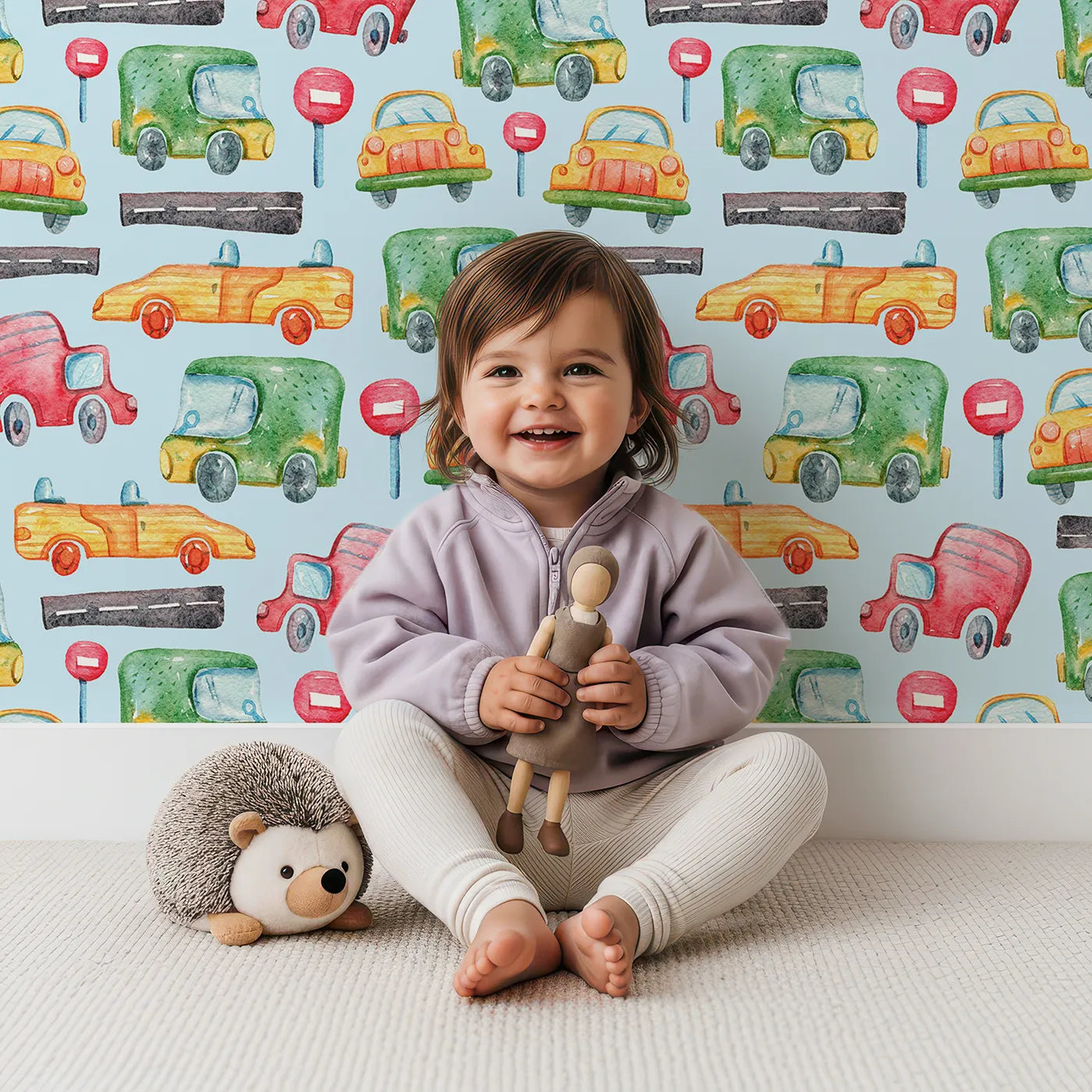 Lovely child standing in front of Whimsy Tots Little Car Parade Wallpaper in Blue with car, sign, road in design.