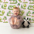 Lovely child standing in front of Whimsy Tots Forest Meadow Grove Wallpaper in Pink with tree, bush in design. Lovely child standing in front of Whimsy Tots Forest Meadow Grove Wallpaper in Pink with tree, bush in design.