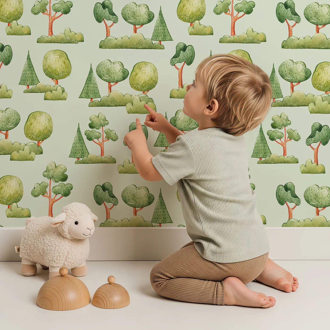 Lovely child standing in front of Whimsy Tots Forest Meadow Grove Wallpaper in Mint Green with tree, bush in design.