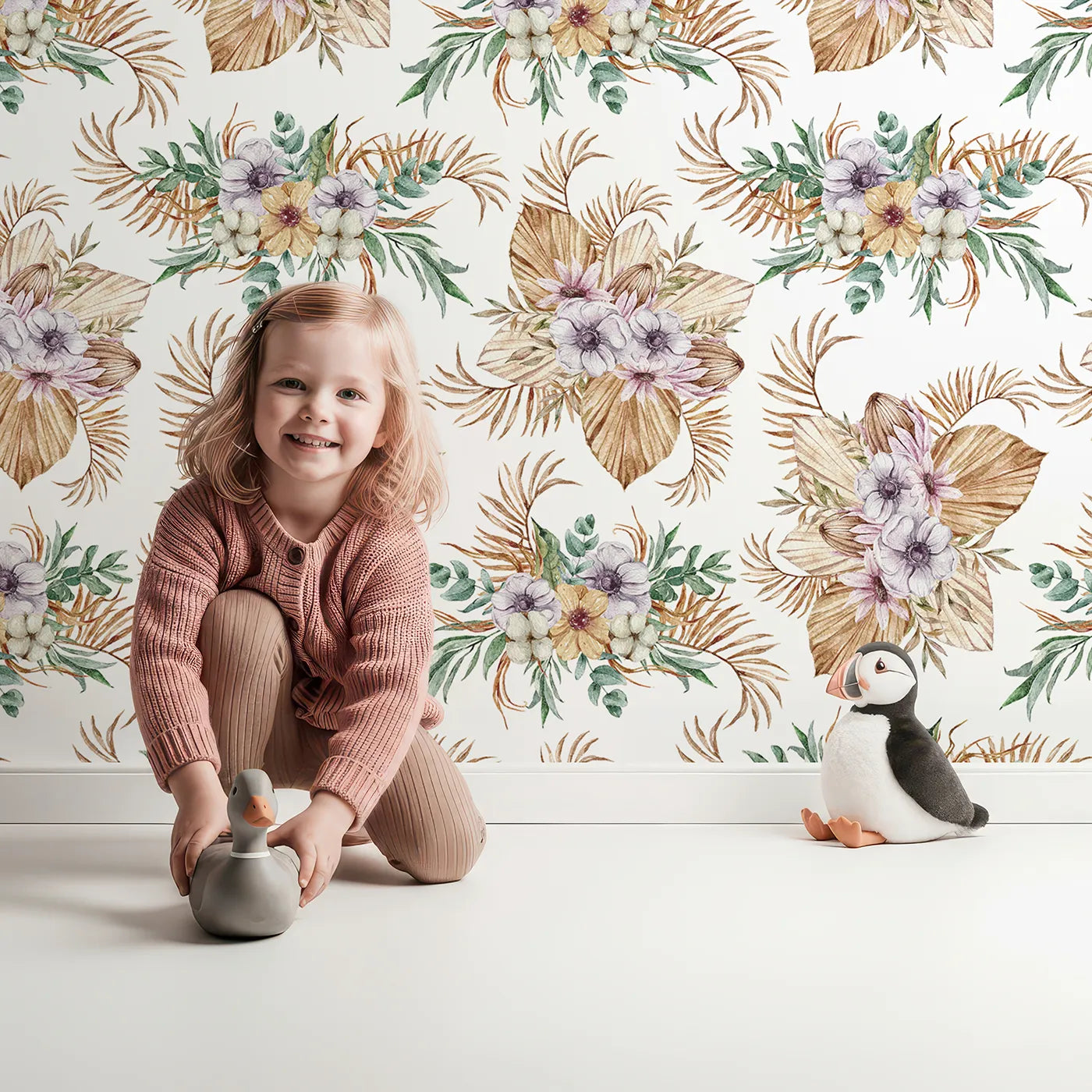Lovely child standing in front of Whimsy Tots Tropical Bloom Medley Wallpaper with flower, palm, leaf, eucalyptus in design.
