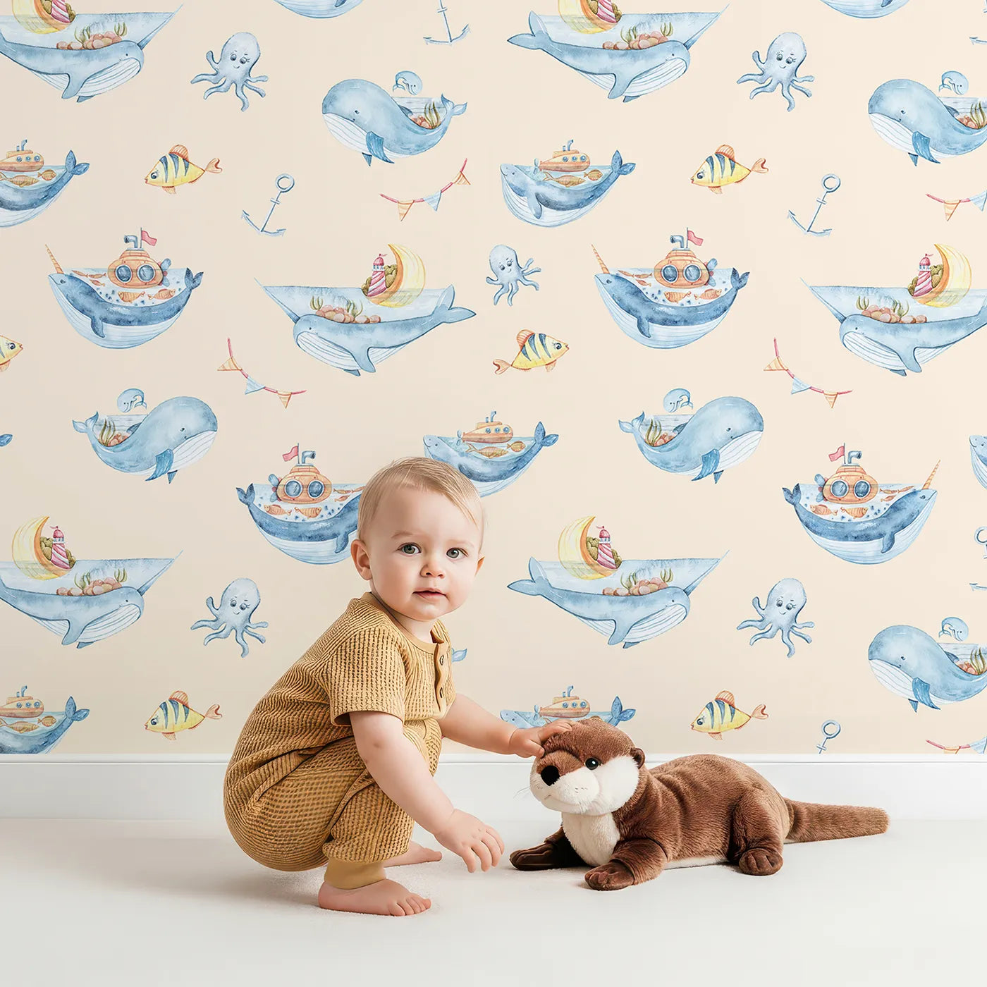 Lovely child standing in front of Whimsy Tots Whale Submarine Adventure Wallpaper in Beige with whale, submarine, fish, anchor, octopus, bunting in design.