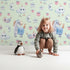 Lovely child standing in front of Whimsy Tots Starlight Narwhal Parade Wallpaper in Mint Green with narwhal, unicorn, moon, star, cloud, heart, fruit in design. Lovely child standing in front of Whimsy Tots Starlight Narwhal Parade Wallpaper in Mint Green with narwhal, unicorn, moon, star, cloud, heart, fruit in design.