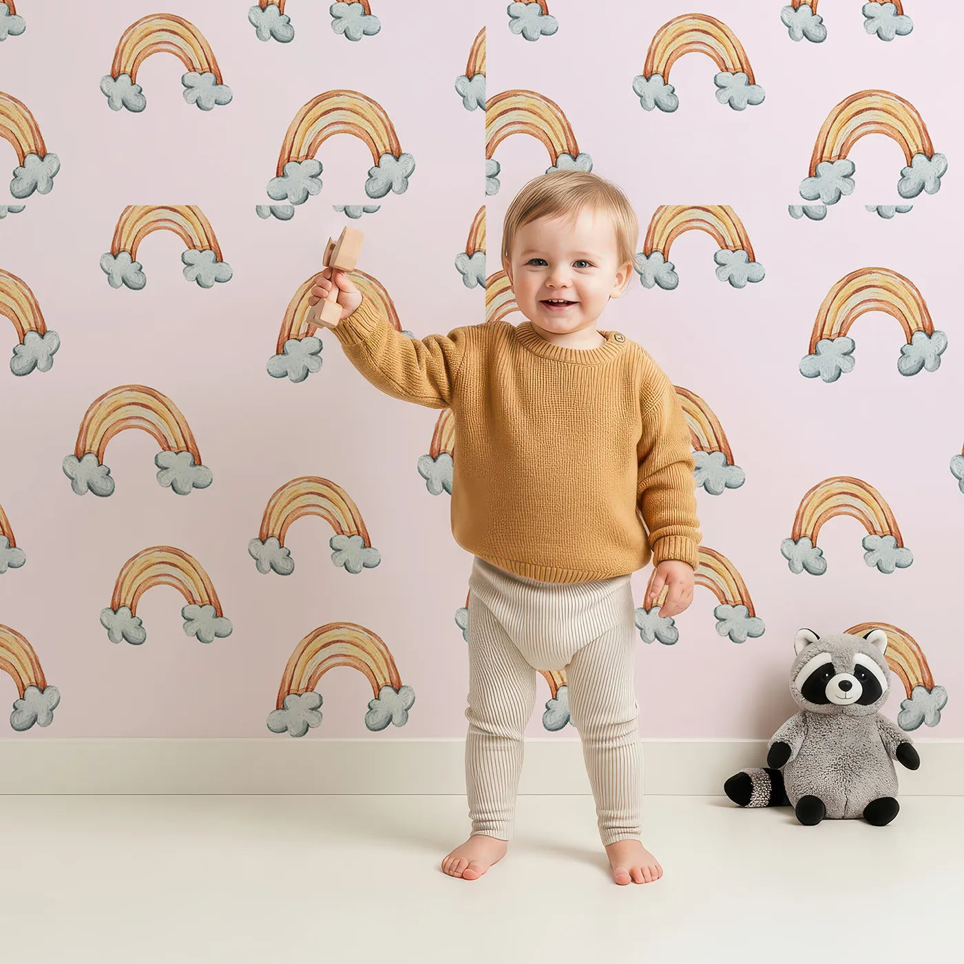 Lovely child standing in front of Whimsy Tots Sunset Rainbows Wallpaper in Pink with rainbow, cloud in design.