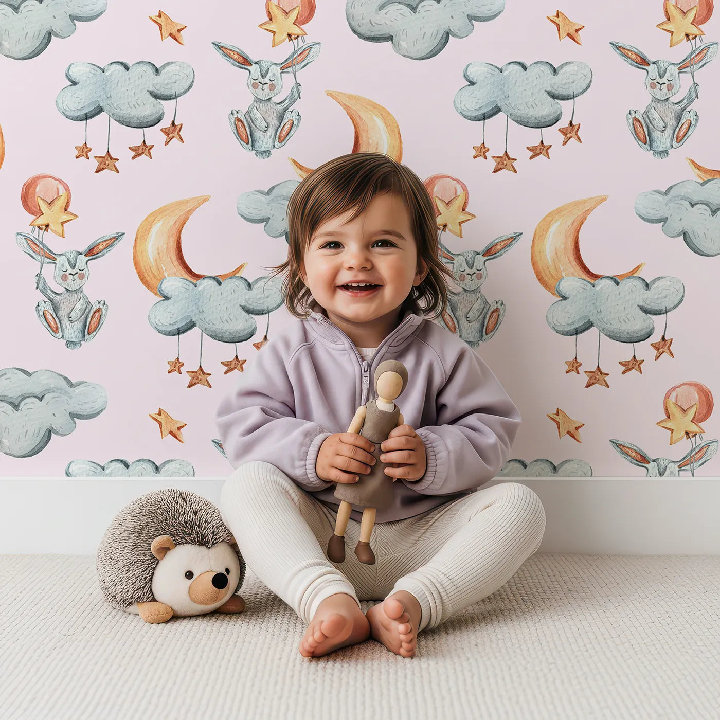 Lovely child standing in front of Whimsy Tots Moonlight Bunny Dreams Wallpaper in Pink with rabbit, balloon, moon, star, cloud in design.