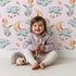 Lovely child standing in front of Whimsy Tots Moonlight Bunny Dreams Wallpaper in Pink with rabbit, balloon, moon, star, cloud in design. Lovely child standing in front of Whimsy Tots Moonlight Bunny Dreams Wallpaper in Pink with rabbit, balloon, moon, star, cloud in design.