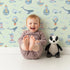 Lovely child standing in front of Whimsy Tots Maritime Whimsy Wallpaper in Mint Green with whale, octopus, boat, sailor, cloud, bulb, bottle in design. Lovely child standing in front of Whimsy Tots Maritime Whimsy Wallpaper in Mint Green with whale, octopus, boat, sailor, cloud, bulb, bottle in design.