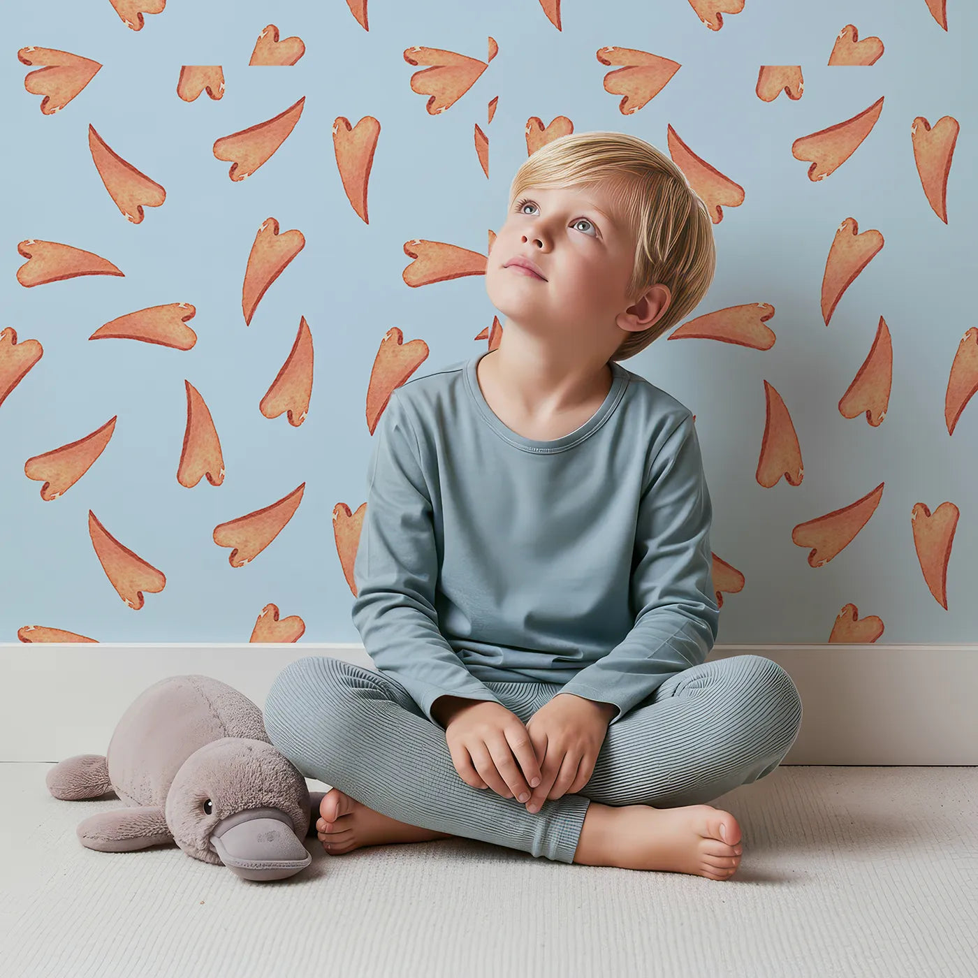 Lovely child standing in front of Whimsy Tots Scattered Heart Sprinkles Wallpaper in Blue with heart, brushstroke, splash in design.