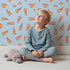 Lovely child standing in front of Whimsy Tots Scattered Heart Sprinkles Wallpaper in Blue with heart, brushstroke, splash in design. Lovely child standing in front of Whimsy Tots Scattered Heart Sprinkles Wallpaper in Blue with heart, brushstroke, splash in design.