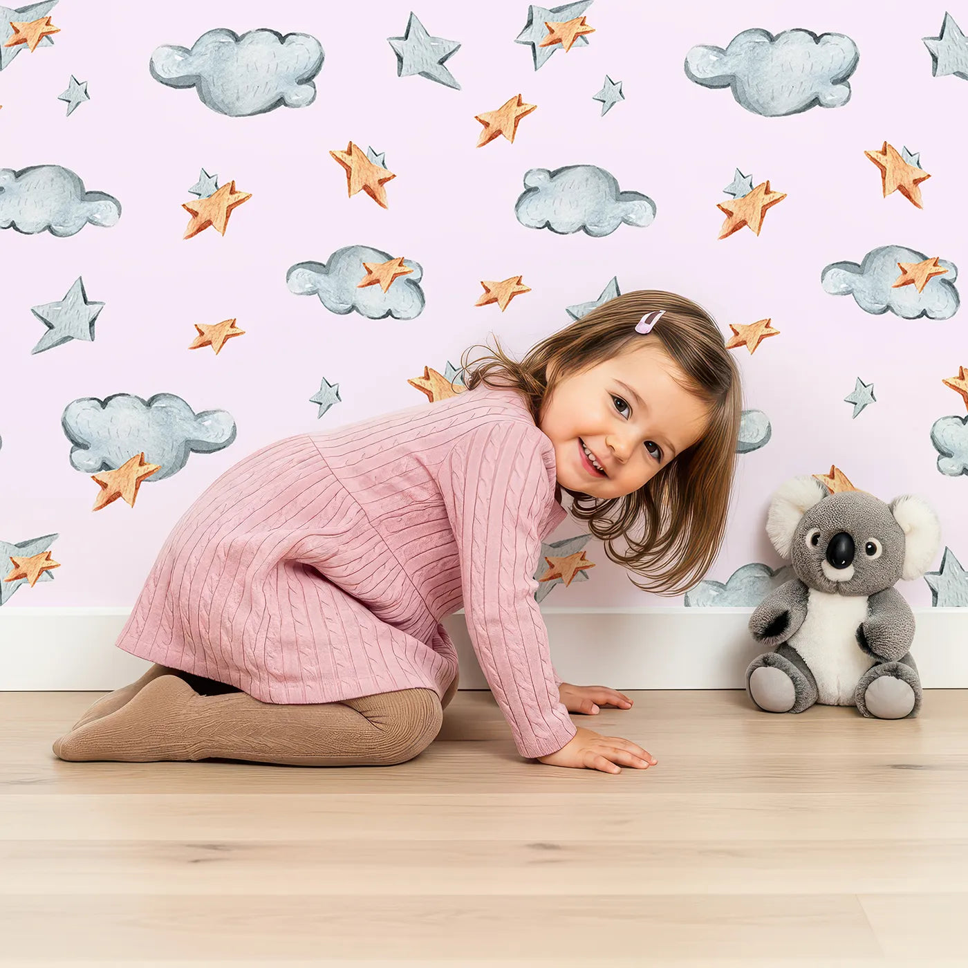 Lovely child standing in front of Whimsy Tots Cloudy Star Drift Wallpaper in Blush Pink with star, cloud in design.