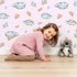Lovely child standing in front of Whimsy Tots Cloudy Star Drift Wallpaper in Blush Pink with star, cloud in design. Lovely child standing in front of Whimsy Tots Cloudy Star Drift Wallpaper in Blush Pink with star, cloud in design.