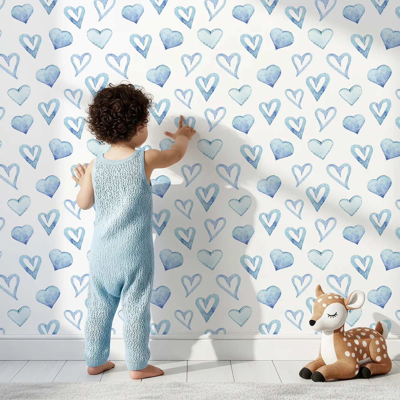 Lovely child standing in front of Whimsy Tots Blue Hearts Wallpaper in White with heart, outline, watercolor in design.