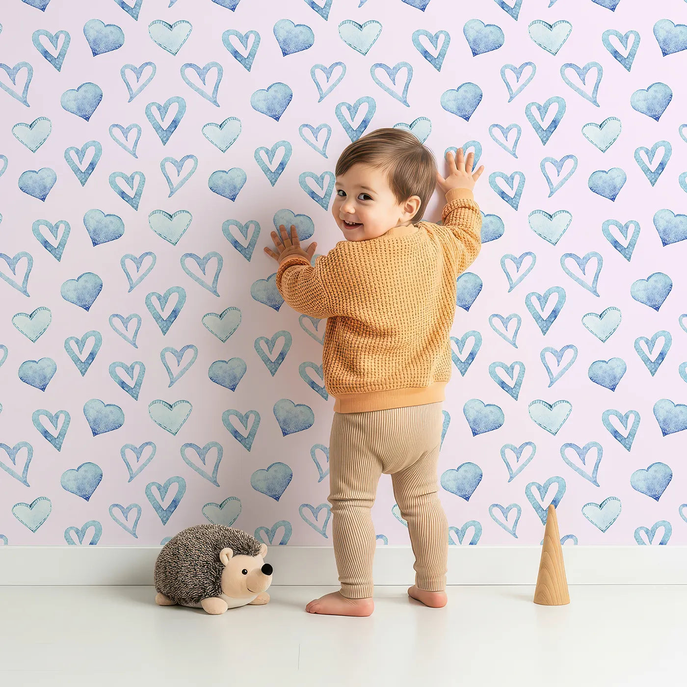 Lovely child standing in front of Whimsy Tots Blue Hearts Wallpaper in Blush with heart, outline, watercolor in design.