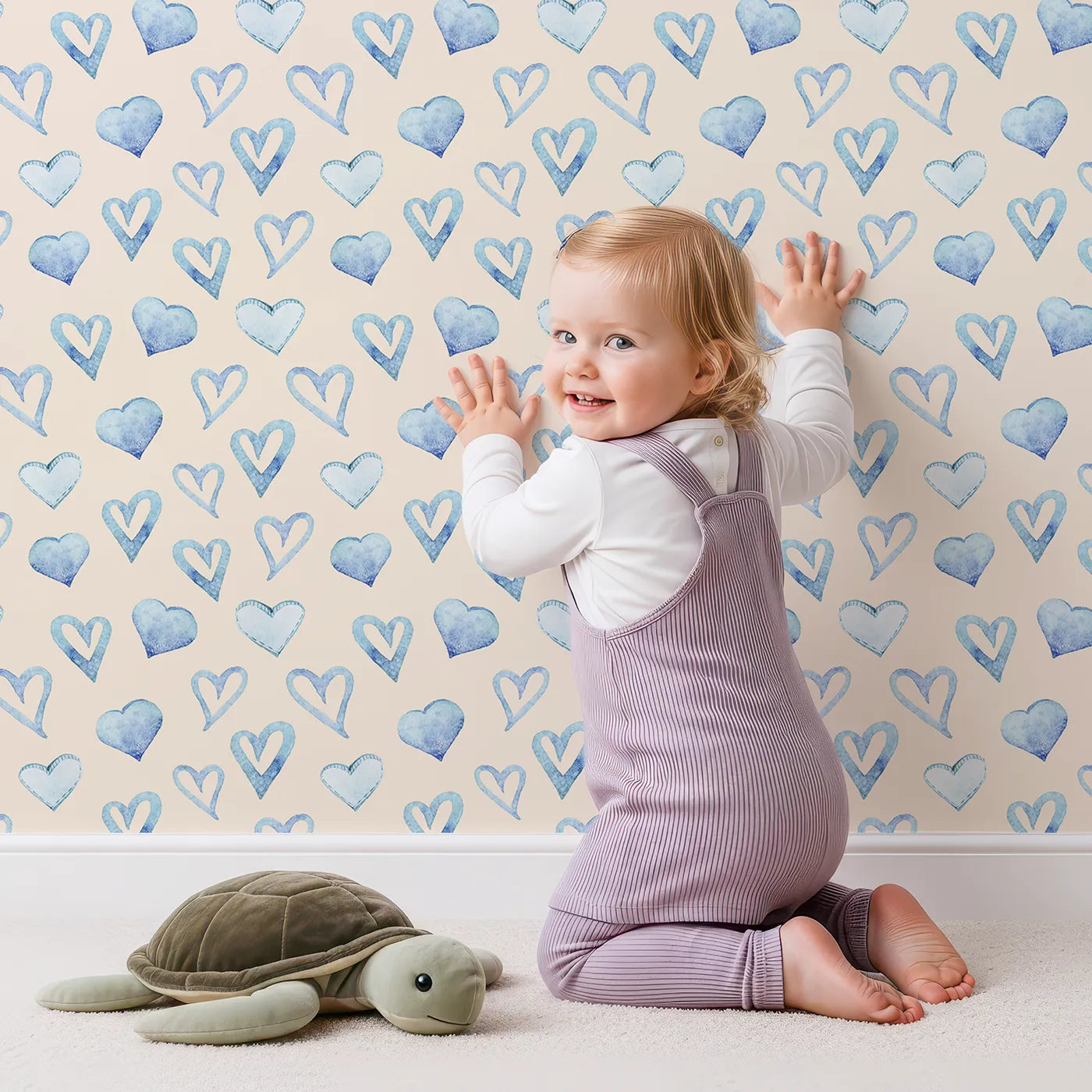 Lovely child standing in front of Whimsy Tots Blue Hearts Wallpaper in Cream with heart, outline, watercolor in design.
