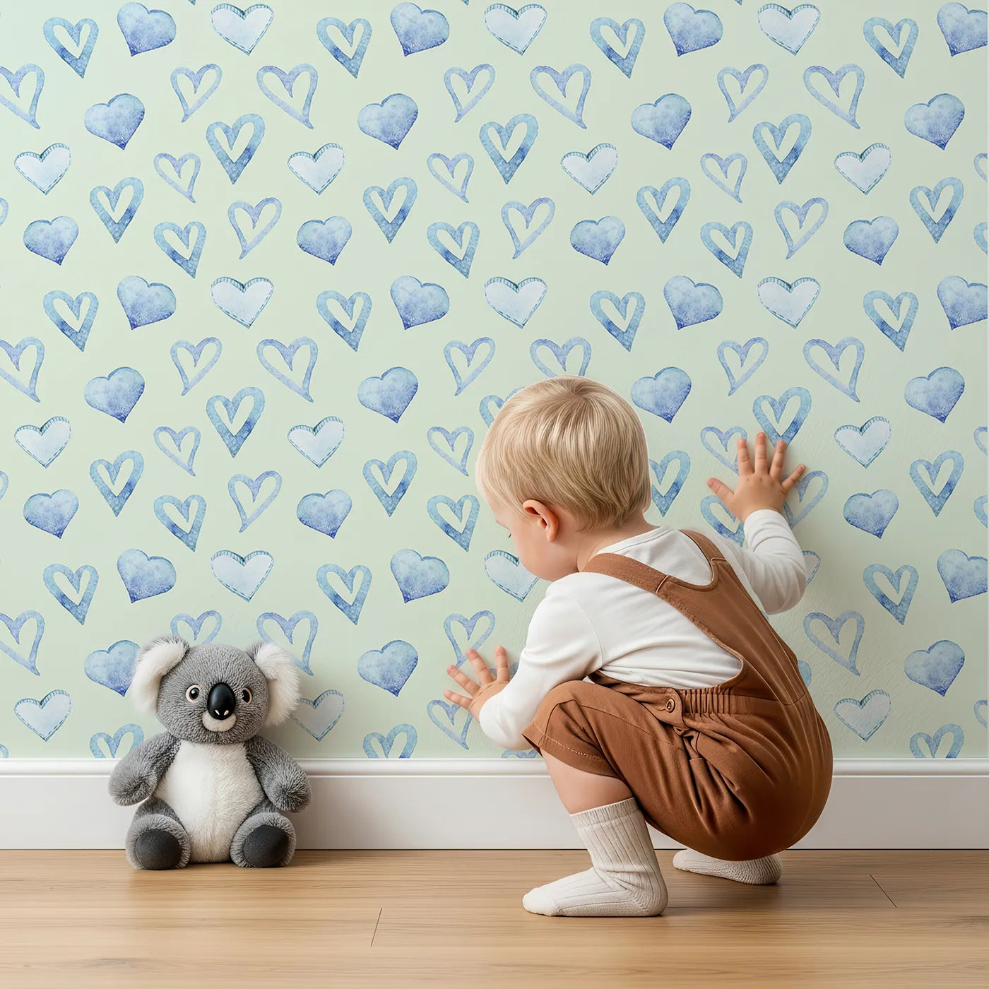 Lovely child standing in front of Whimsy Tots Blue Hearts Wallpaper in Mint with heart, outline, watercolor in design.