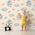 Lovely child standing in front of Whimsy Tots Bunny Cloud Dreams Wallpaper in Cream with bunny, cloud, star, string, moon in design. Lovely child standing in front of Whimsy Tots Bunny Cloud Dreams Wallpaper in Cream with bunny, cloud, star, string, moon in design.