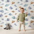 Lovely child standing in front of Whimsy Tots Dreamy Fish Parade Wallpaper in White with fish, fin, puffer, anglerfish, goby in design. Lovely child standing in front of Whimsy Tots Dreamy Fish Parade Wallpaper in White with fish, fin, puffer, anglerfish, goby in design.