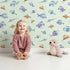 Lovely child standing in front of Whimsy Tots Dreamy Fish Parade Wallpaper in Green with fish, fin, puffer, anglerfish, goby in design. Lovely child standing in front of Whimsy Tots Dreamy Fish Parade Wallpaper in Green with fish, fin, puffer, anglerfish, goby in design.