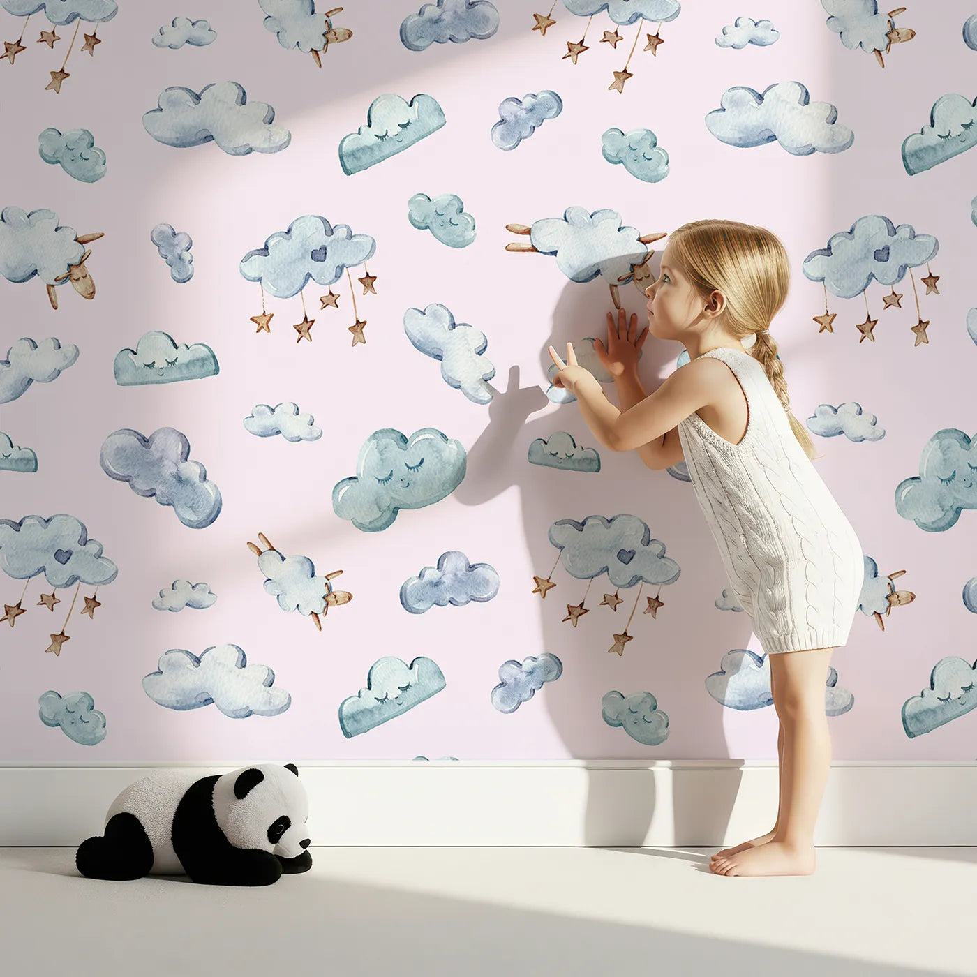Lovely child standing in front of Whimsy Tots Counting Cloud Sheep Wallpaper in Blush Pink with cloud, sheep, star, mobile in design.