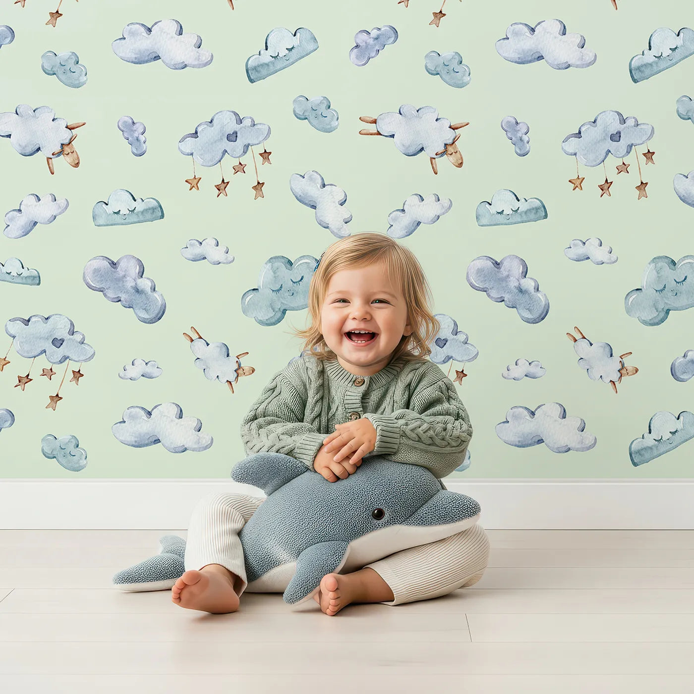 Lovely child standing in front of Whimsy Tots Counting Cloud Sheep Wallpaper in Mint Green with cloud, sheep, star, mobile in design.
