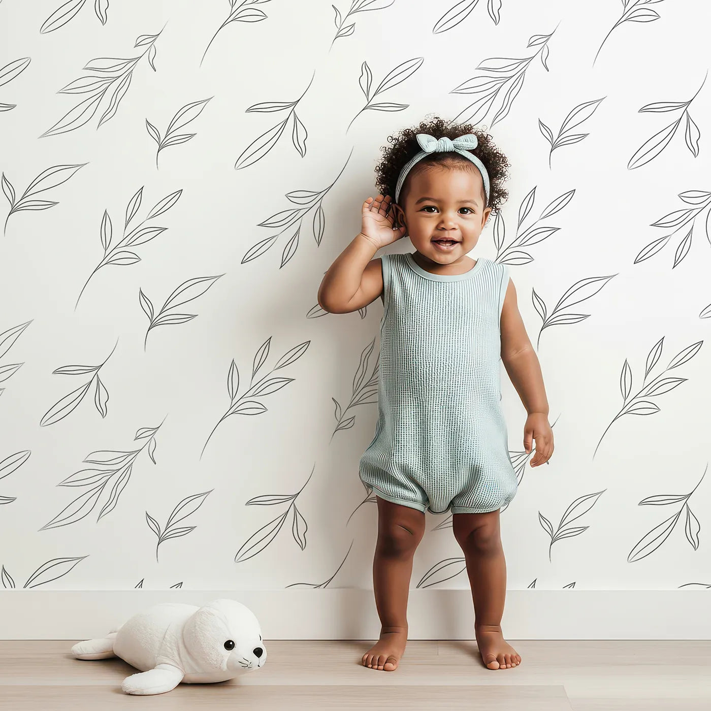 Lovely child standing in front of Whimsy Tots Line Art Leaf Dance Wallpaper in White with leaf, branch, botanical, outline in design.