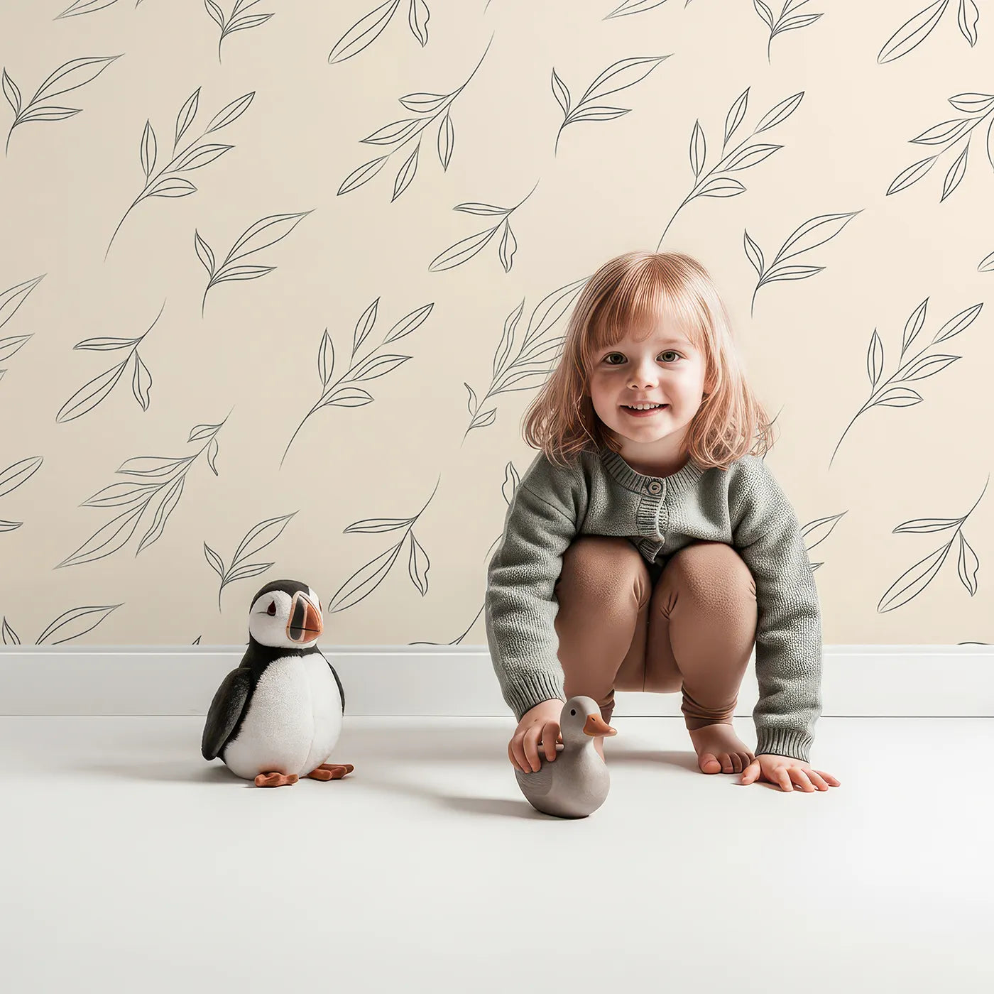 Lovely child standing in front of Whimsy Tots Line Art Leaf Dance Wallpaper in Beige with leaf, branch, botanical, outline in design.