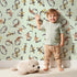 Lovely child standing in front of Whimsy Tots Botanical Numbers Garden in Mint Green with number, leaf, branch, stem in design. Lovely child standing in front of Whimsy Tots Botanical Numbers Garden in Mint Green with number, leaf, branch, stem in design.