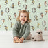 Lovely child standing in front of Whimsy Tots Botanical Numbers Grid in Mint Green with number, leaf, branch, stem in design. Lovely child standing in front of Whimsy Tots Botanical Numbers Grid in Mint Green with number, leaf, branch, stem in design.