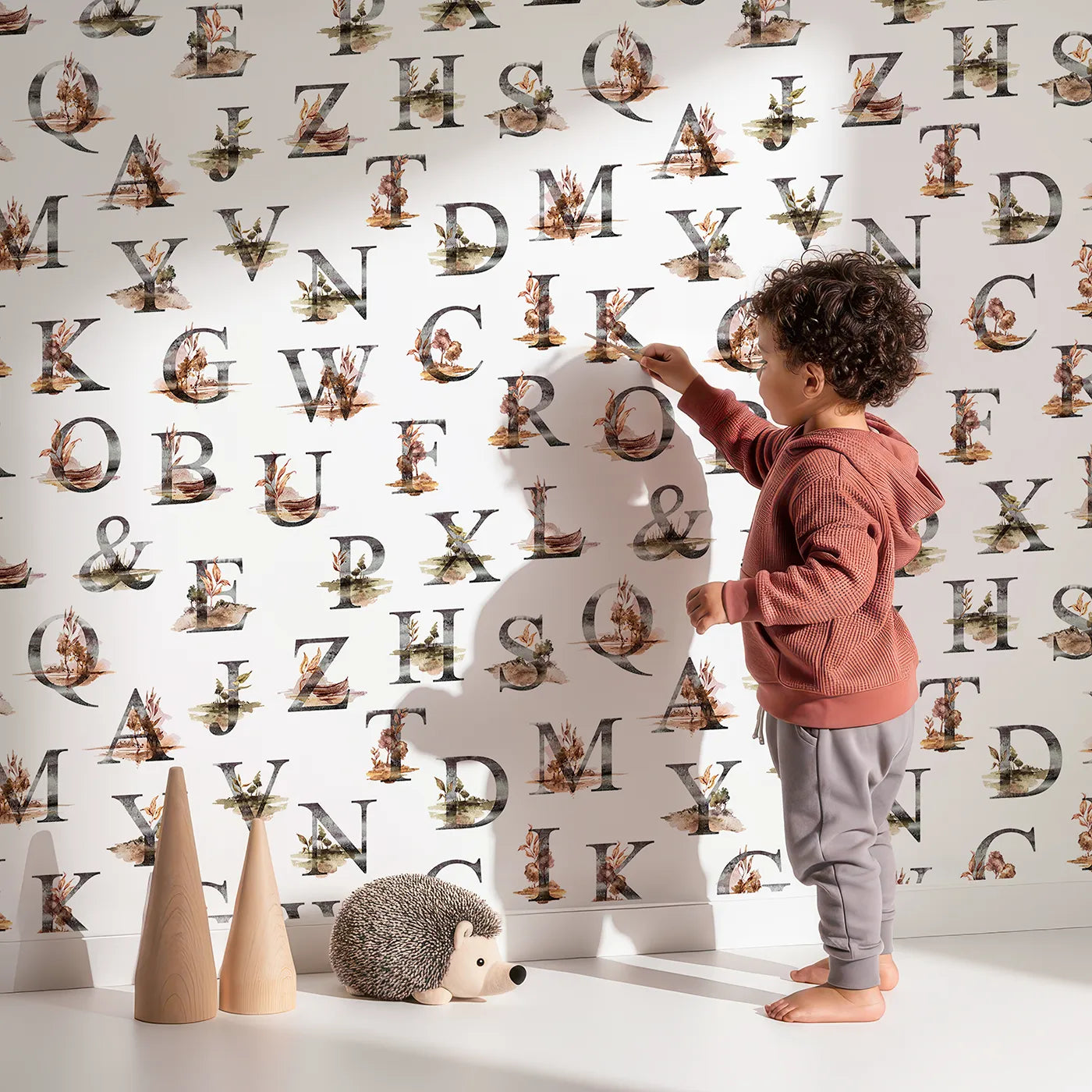 Lovely child standing in front of Whimsy Tots Rustic Alphabet Adventure in White with letter, alphabet, tree, boat, plant in design.