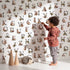 Lovely child standing in front of Whimsy Tots Rustic Alphabet Adventure in White with letter, alphabet, tree, boat, plant in design. Lovely child standing in front of Whimsy Tots Rustic Alphabet Adventure in White with letter, alphabet, tree, boat, plant in design.