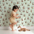 Lovely child standing in front of Whimsy Tots Rustic Alphabet Adventure in Mint Green with letter, alphabet, tree, boat, plant in design. Lovely child standing in front of Whimsy Tots Rustic Alphabet Adventure in Mint Green with letter, alphabet, tree, boat, plant in design.