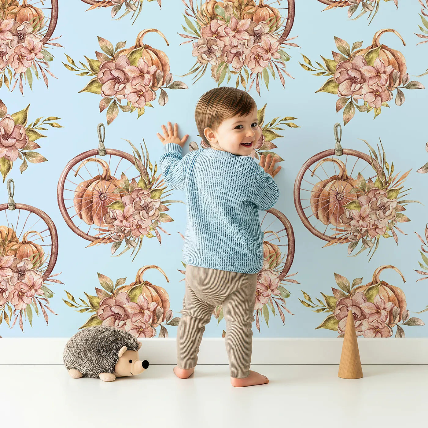 Lovely child standing in front of Whimsy Tots Harvest Bloom Hoop Wallpaper in Blue with flower, pumpkin, hoop, leaf in design.