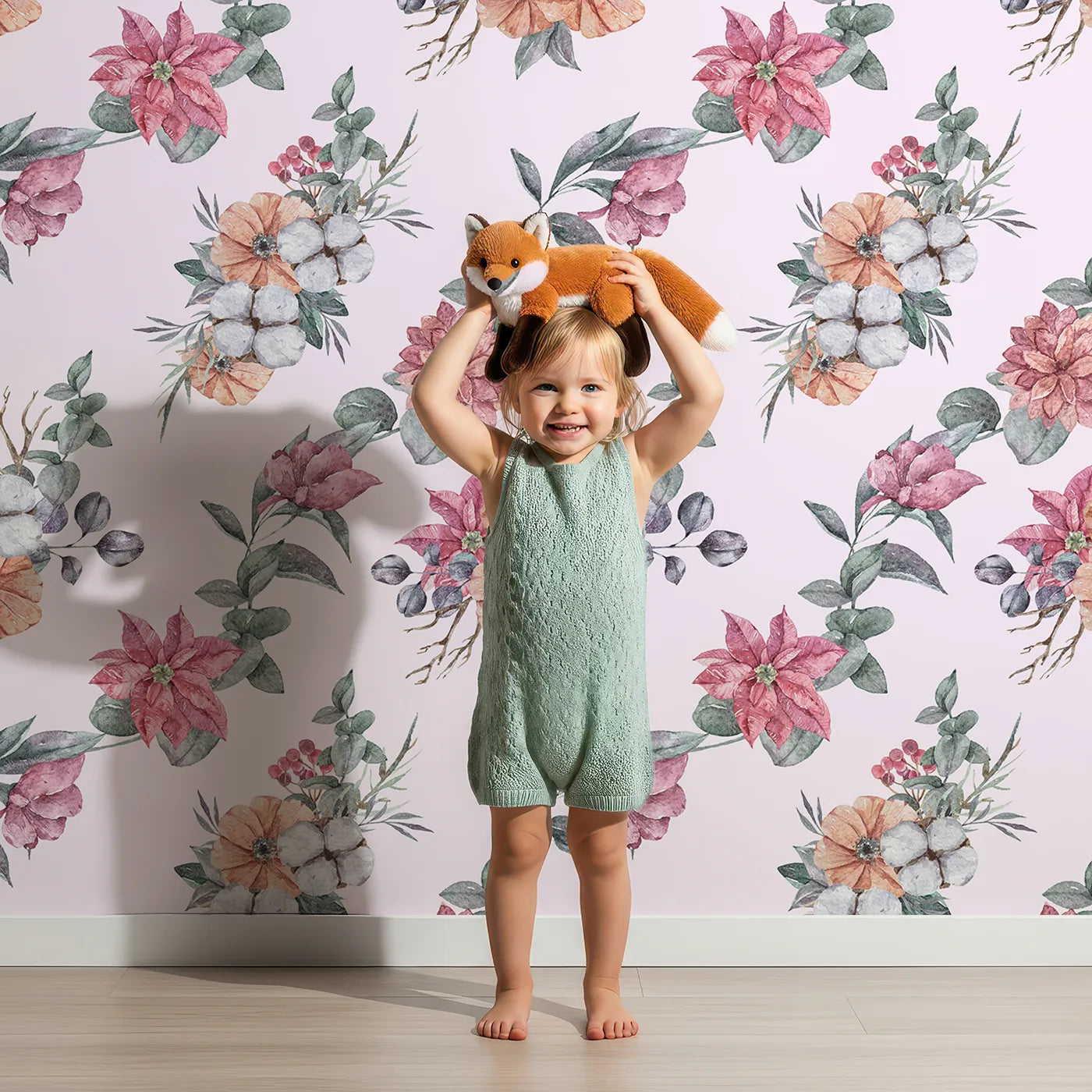 Lovely child standing in front of Whimsy Tots Winter Blooming Garden Wallpaper in Blush Pink with flower, cotton, eucalyptus, poinsettia in design.
